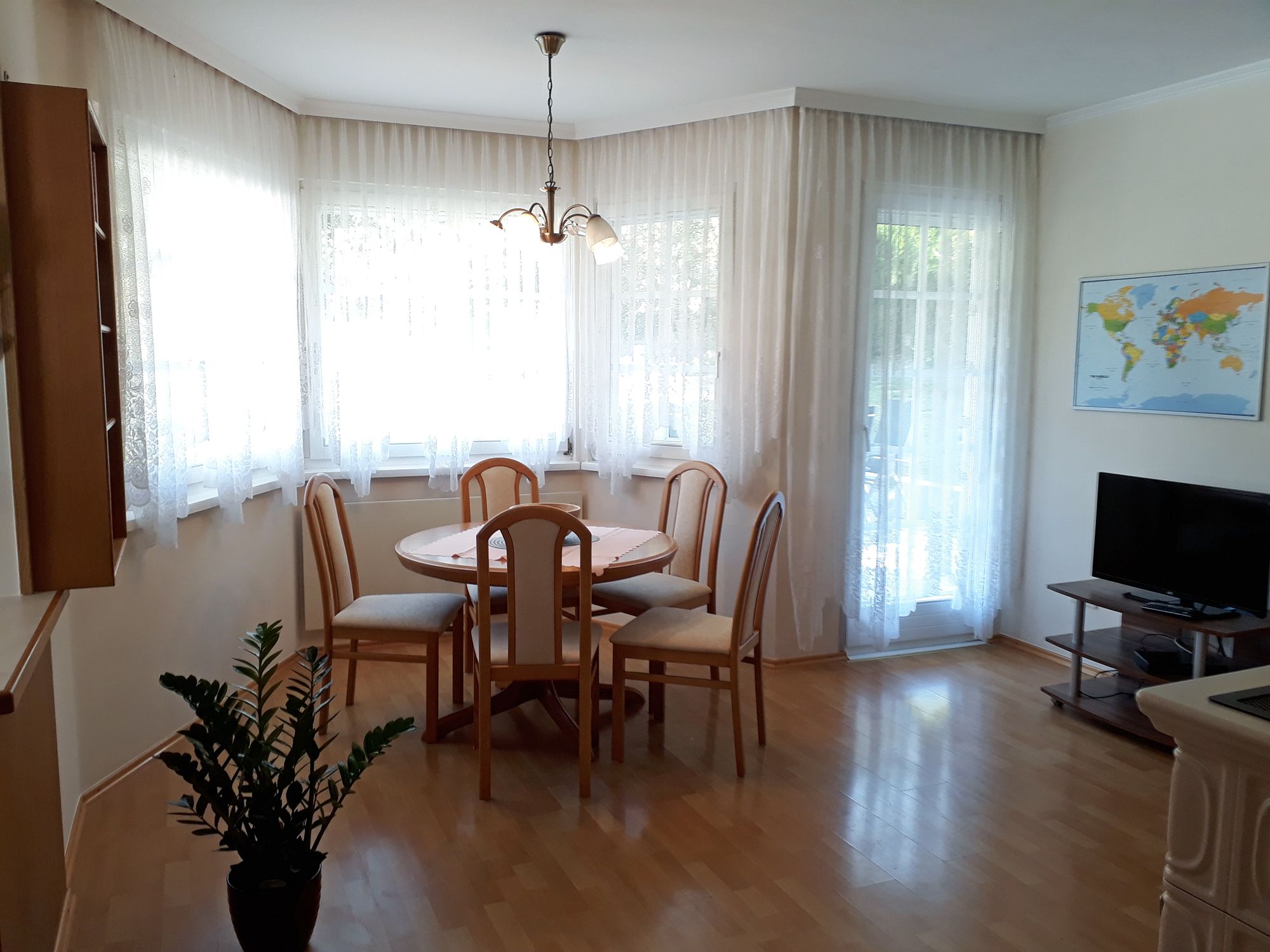 Bright eat-in kitchen with dining table, chairs, TV and world map on the wall.