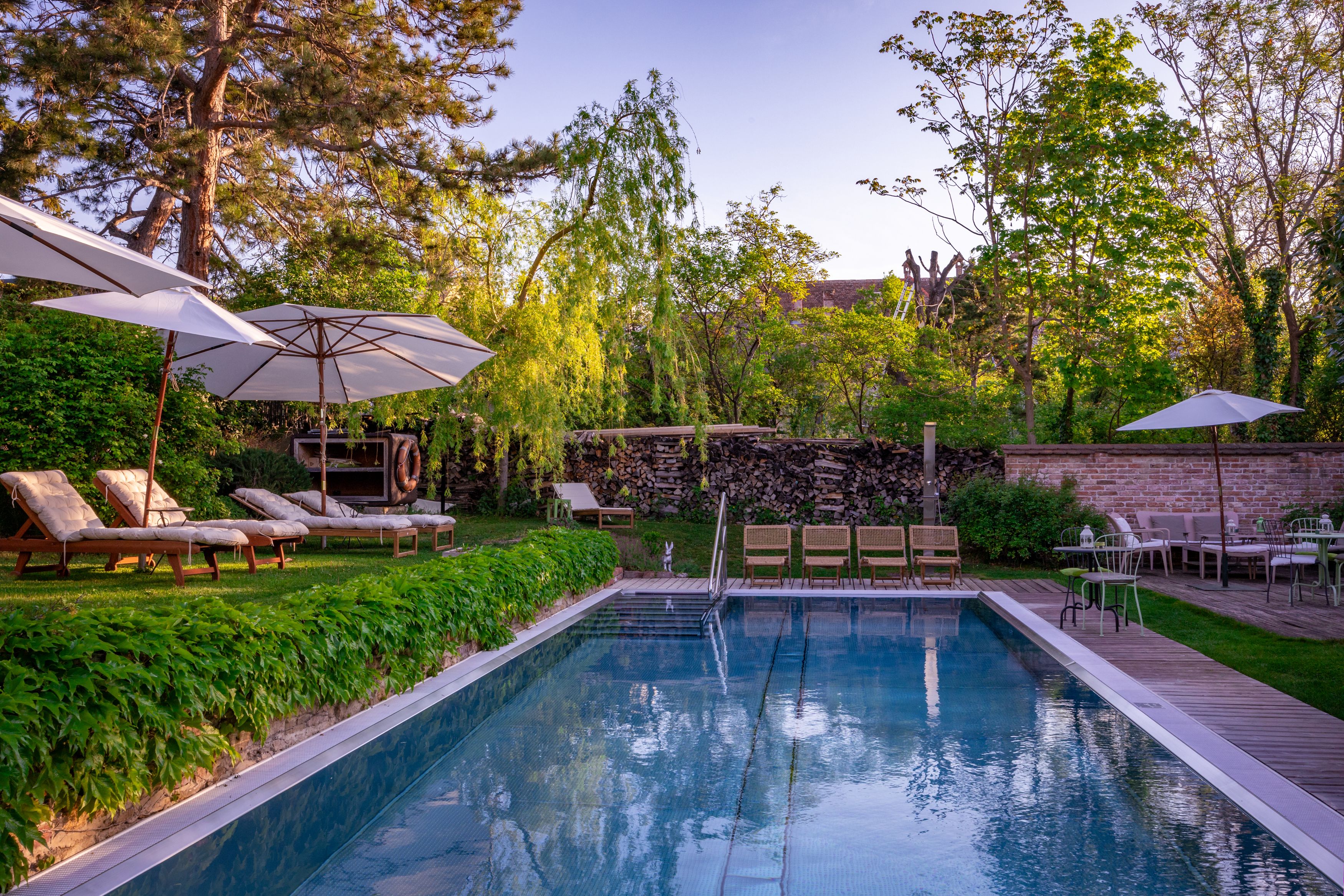 Garden with pool, sun loungers and parasols at Hotel Landhaus Moserhof.