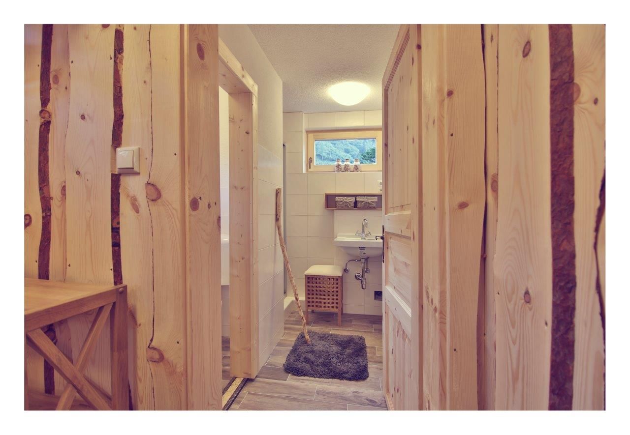 Interior view of a bathroom in a chalet with wooden walls and doors, washbasin and small window.
