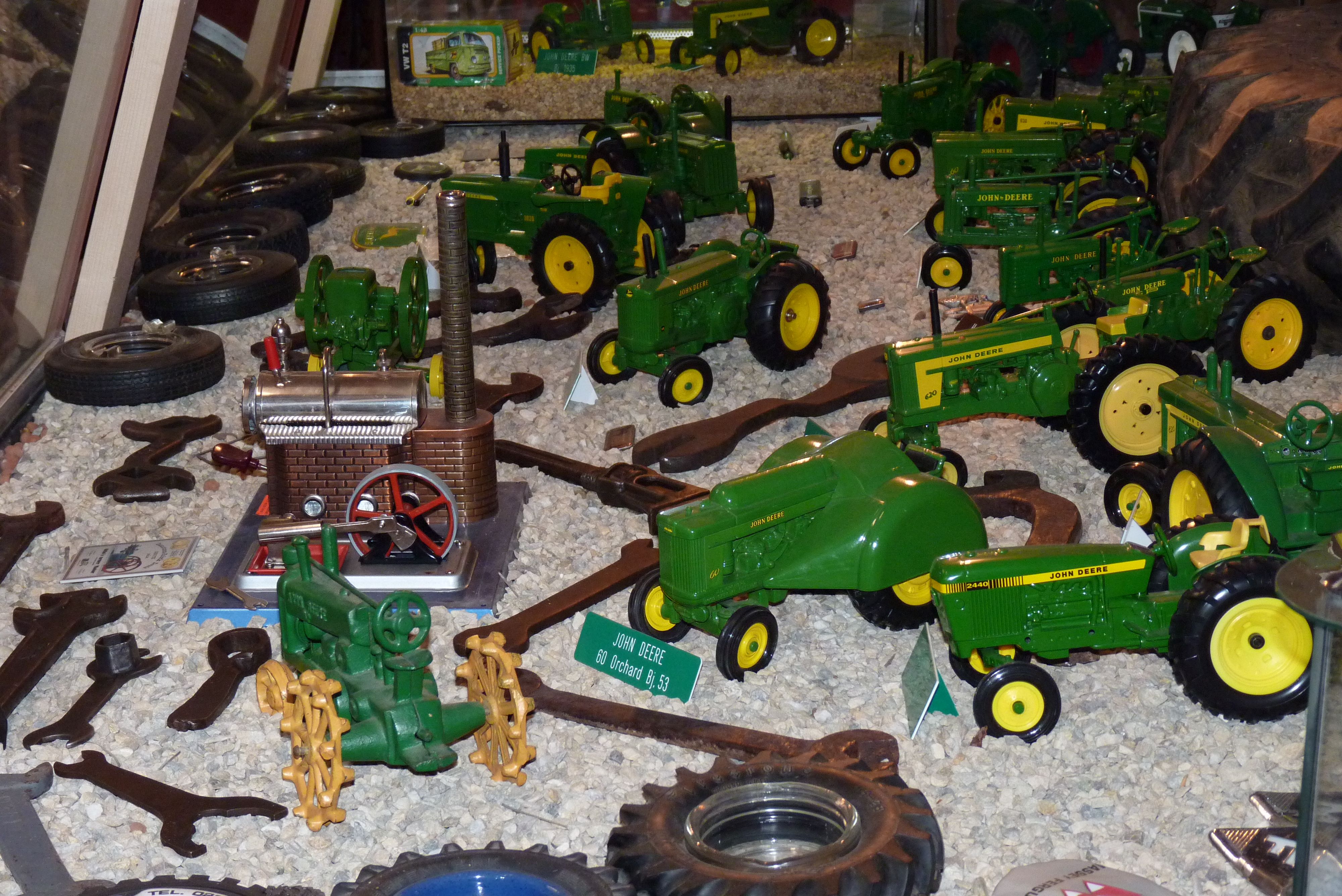 Collection of model tractors exhibited on gravel.