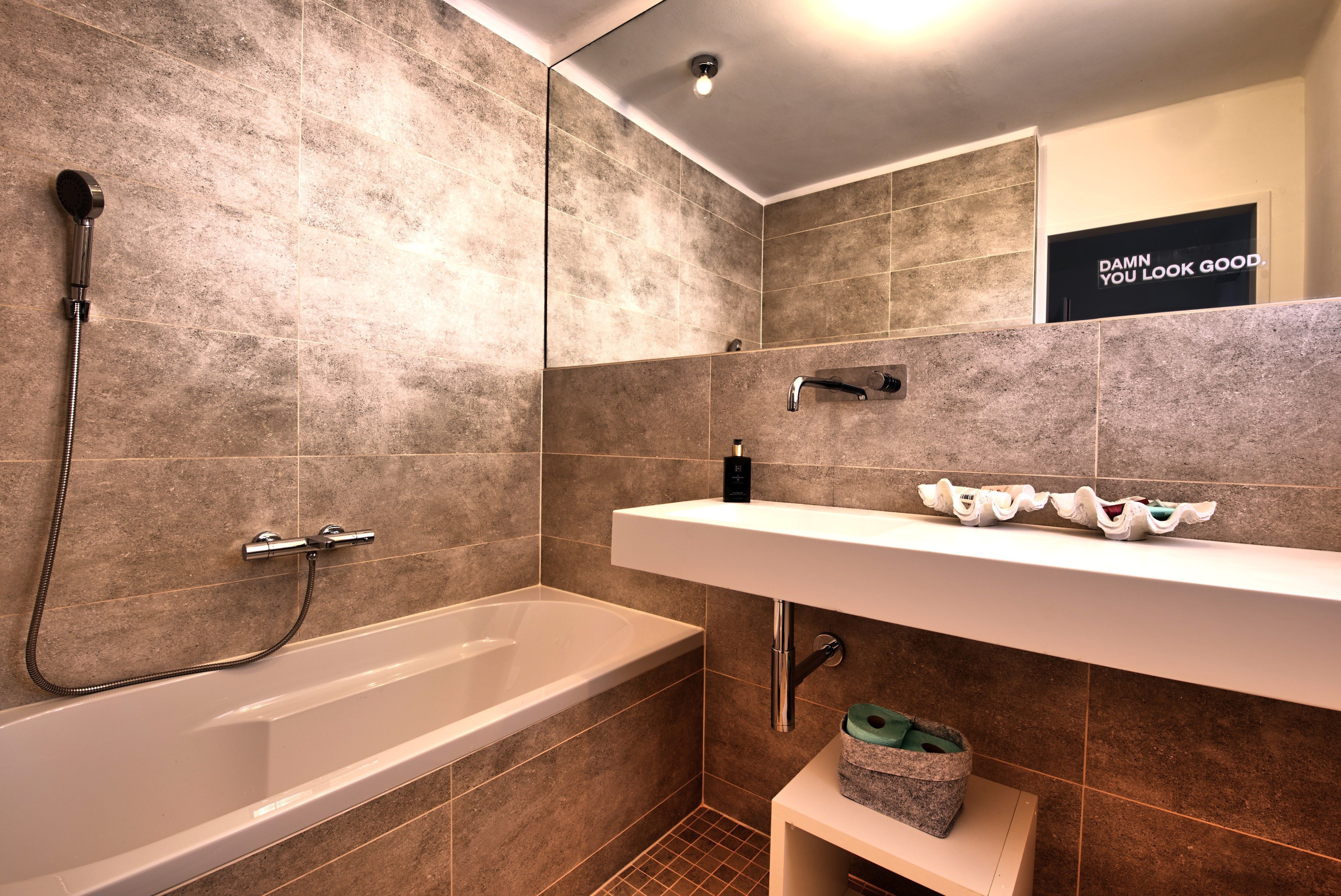 Modern bathroom with bathtub, washbasin and large mirror.