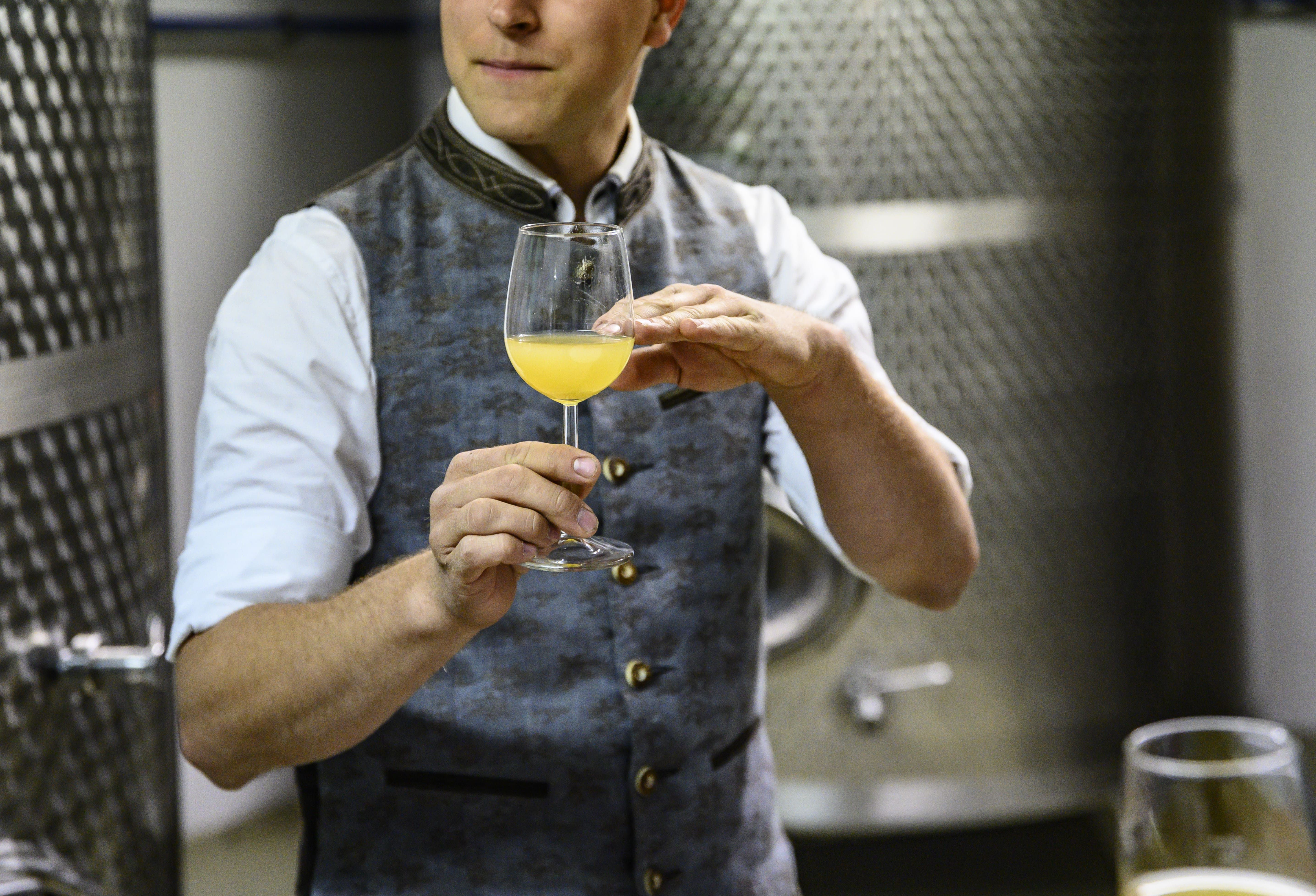 Person in traditional clothing holding a glass of Cider
