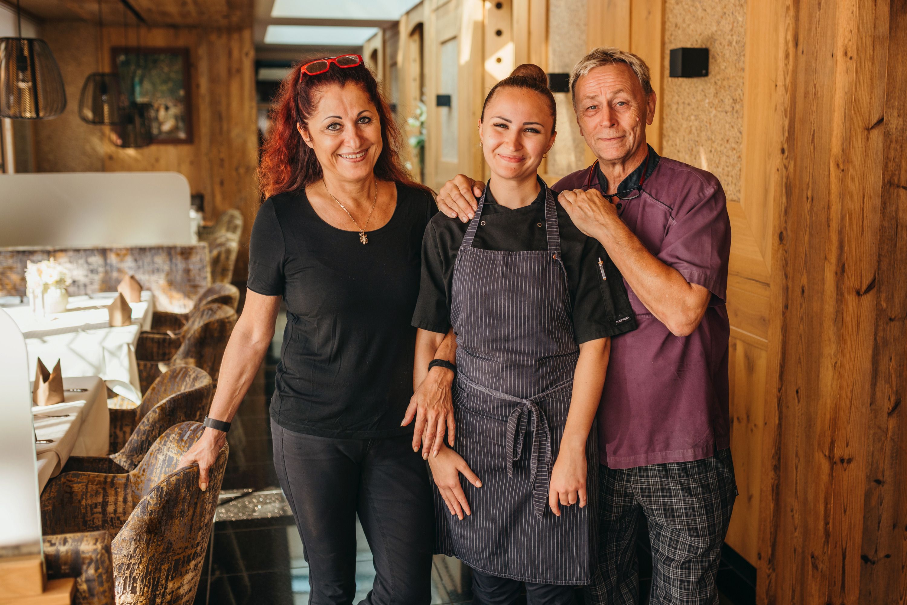 Three people in a cozy restaurant, smiling and friendly.