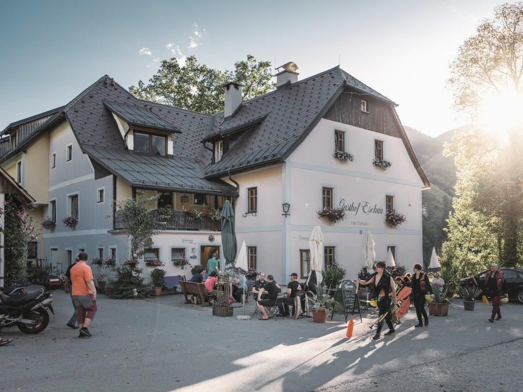 A traditional inn with people outside in the sunshine.
