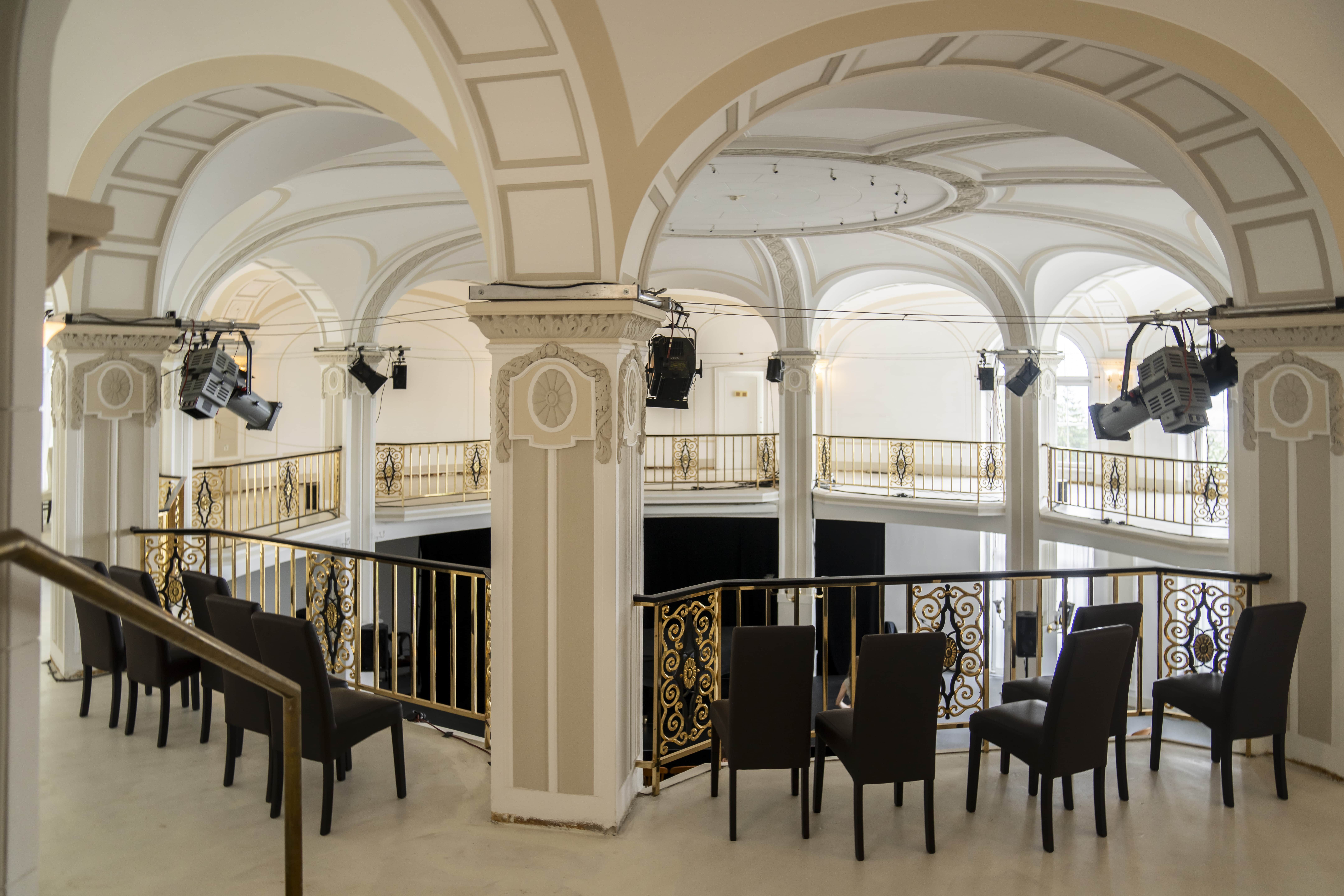 Interior view of an elegant hall with arches and golden railings.