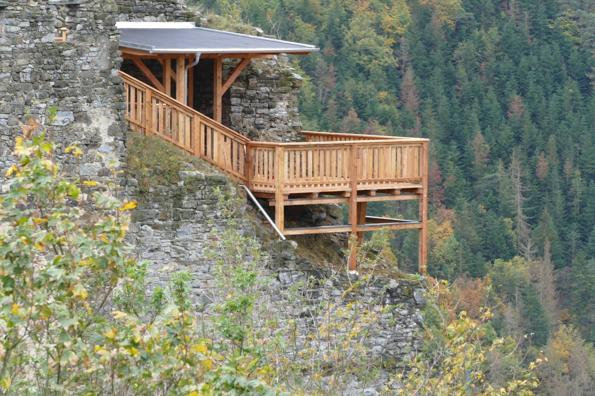 Wooden platform at a castle ruin with forest in the background.