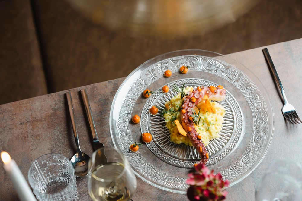 Elegant dish with octopus and garnish served on a glass plate.