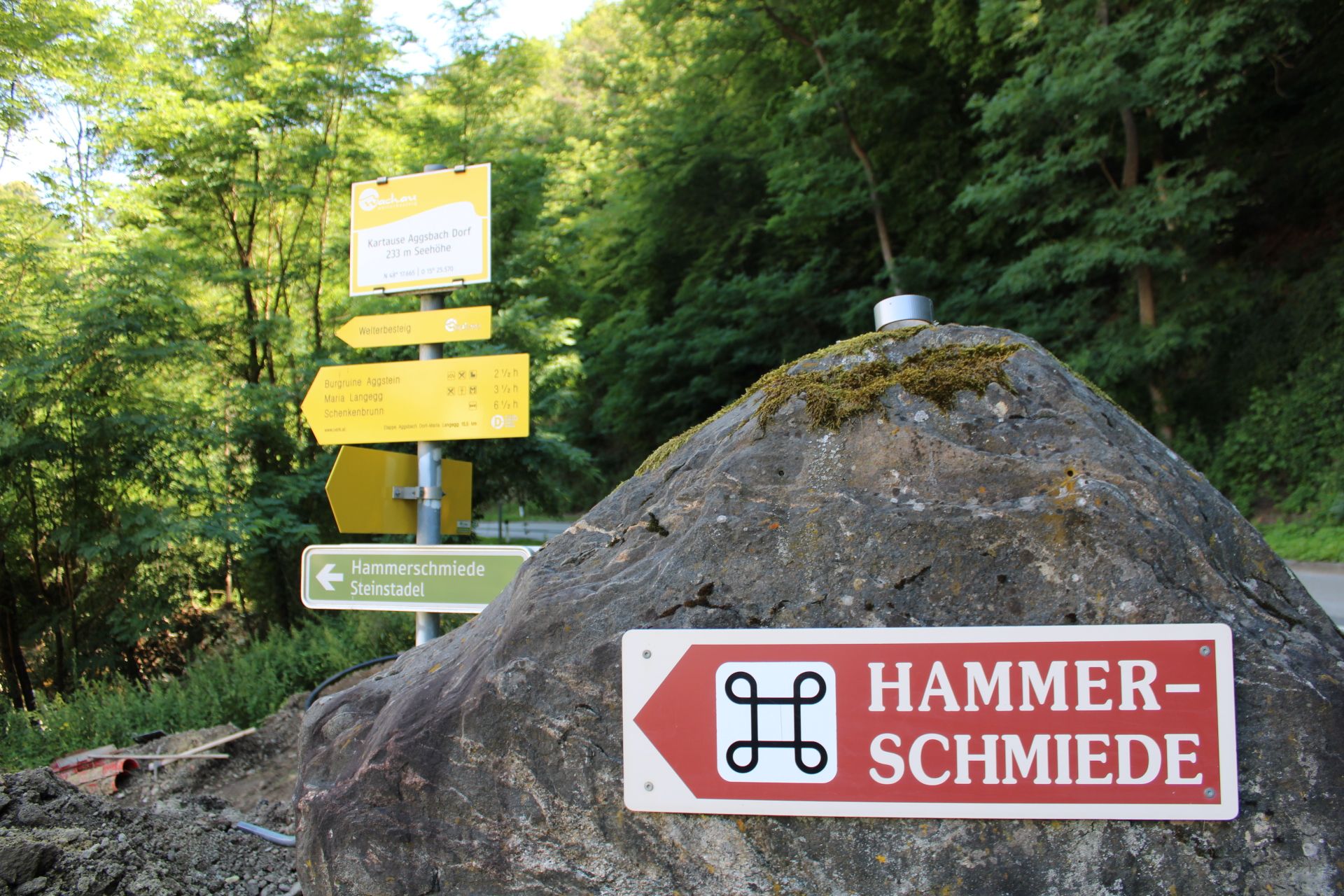 Signpost to the hammer mill in Aggsbach, surrounded by trees.