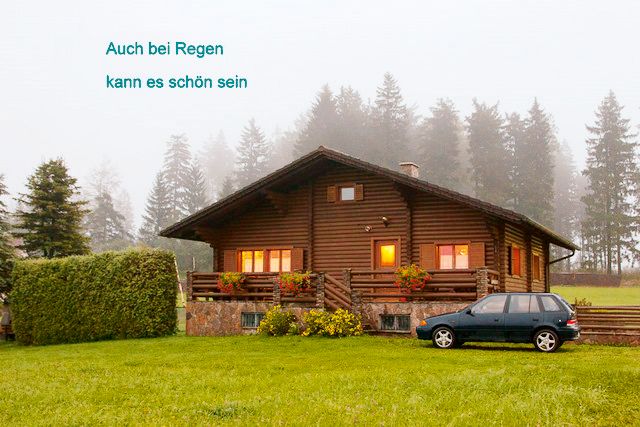 Log cabin in the fog with car and trees in the background.