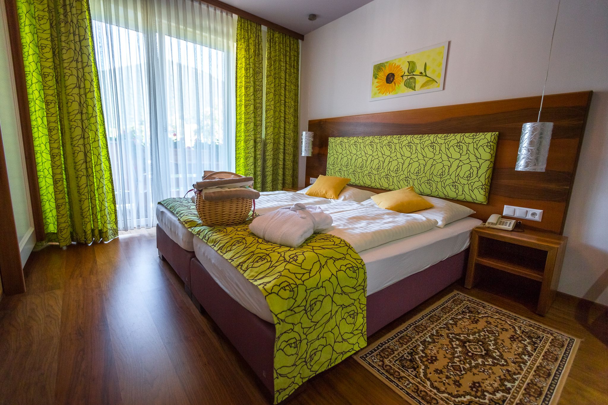 Room with double bed, wooden floor and green curtains
