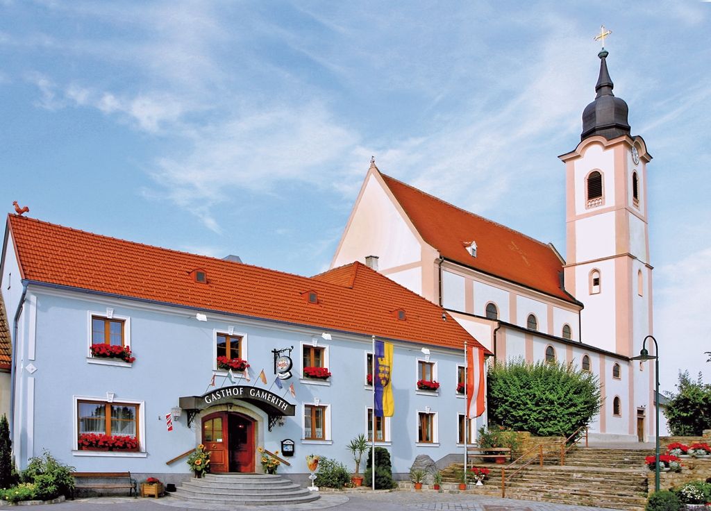 Gasthaus Gamerith next to a church with a tower and red roof.