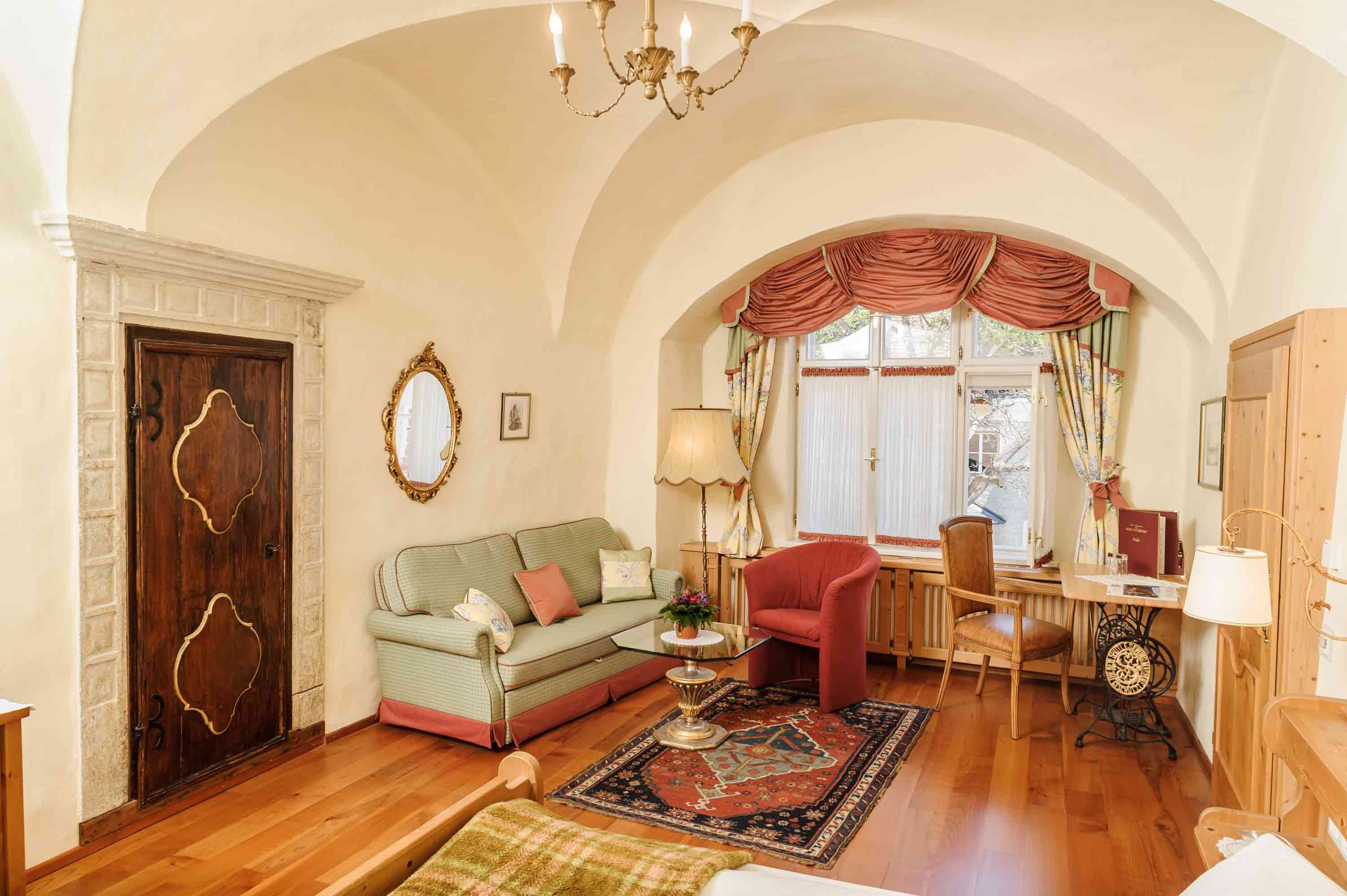 Cozy living room with antique flair, sofa, carpet, table and window with curtains.