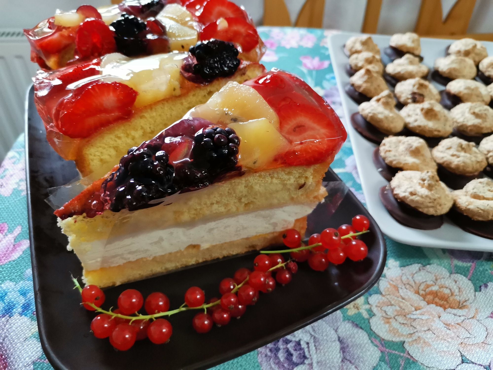 Fruit cake with berries and cookies on a table.