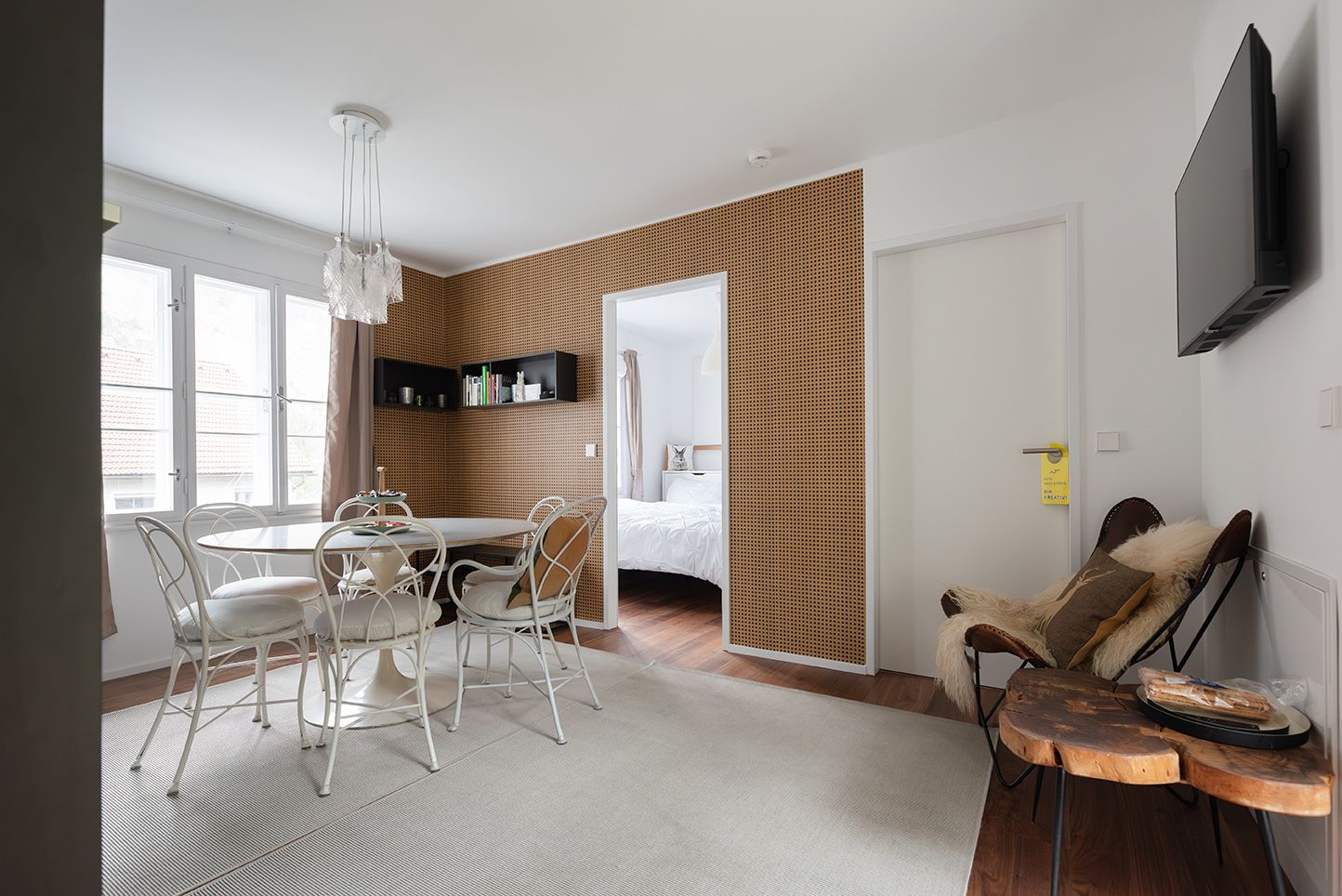 Modern furnished room with dining table, chairs and an adjoining bedroom.