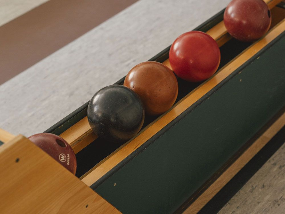 Skittle alley with four skittle balls in a holder.