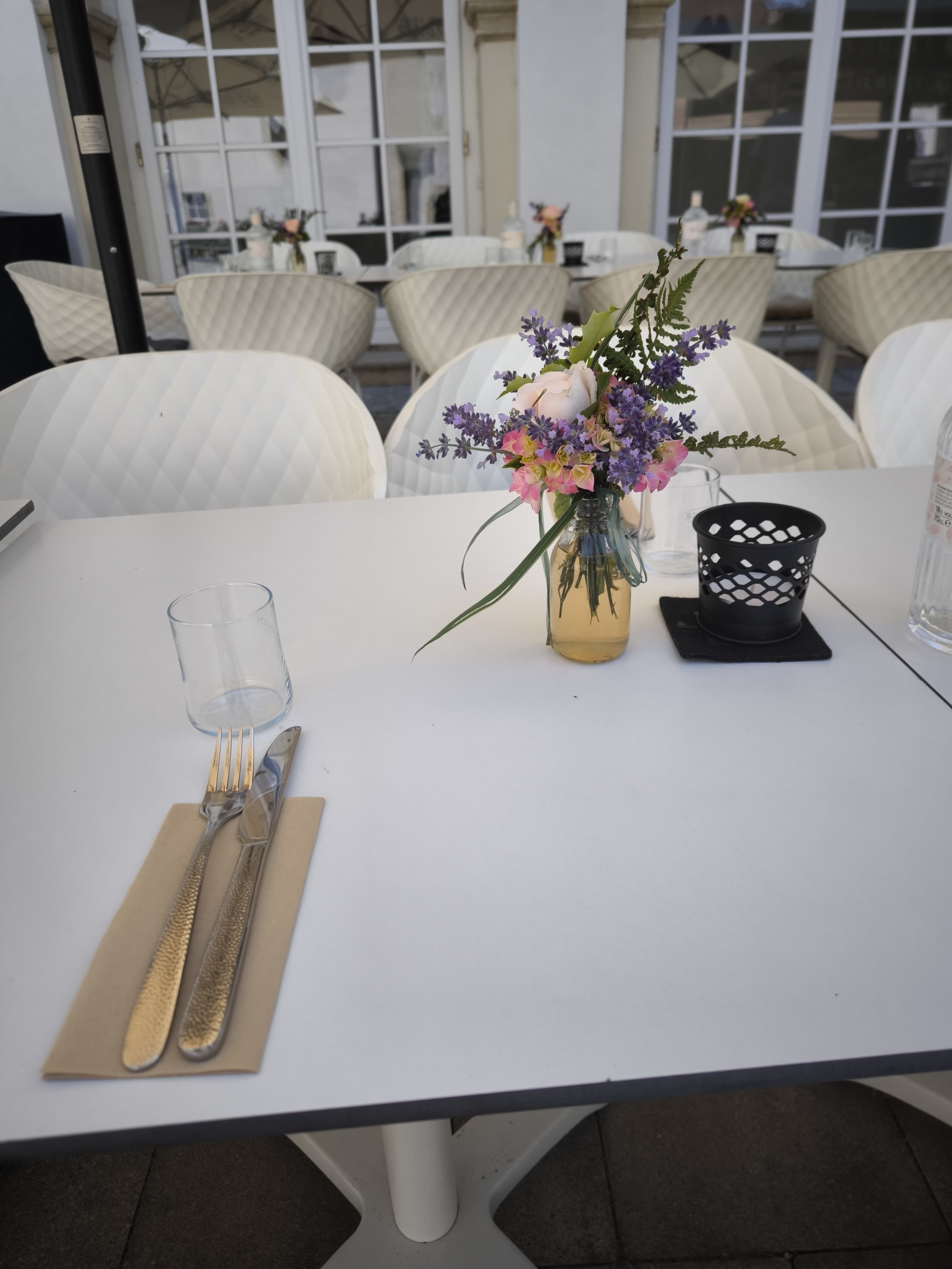 Set table on a terrace with a bouquet of flowers and cutlery.