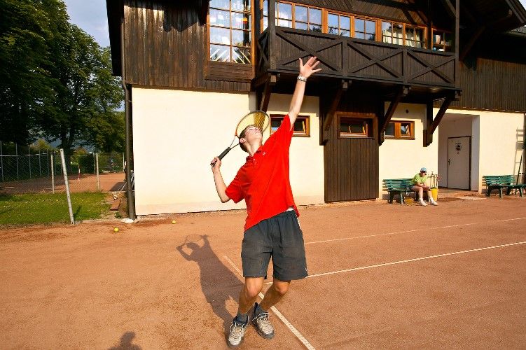 Person playing tennis in front of a building.