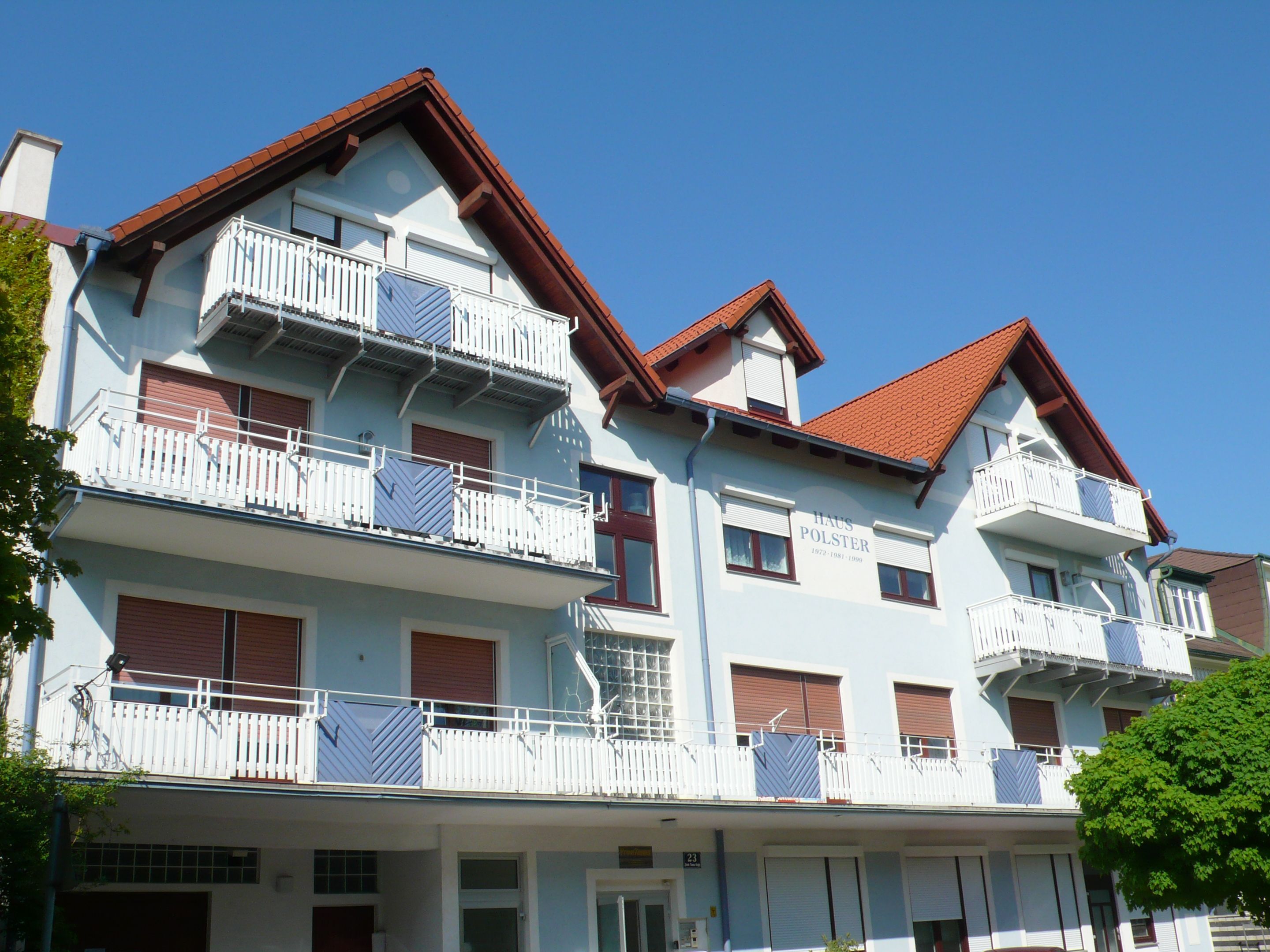 Multi-storey building with blue façade and red roofs.