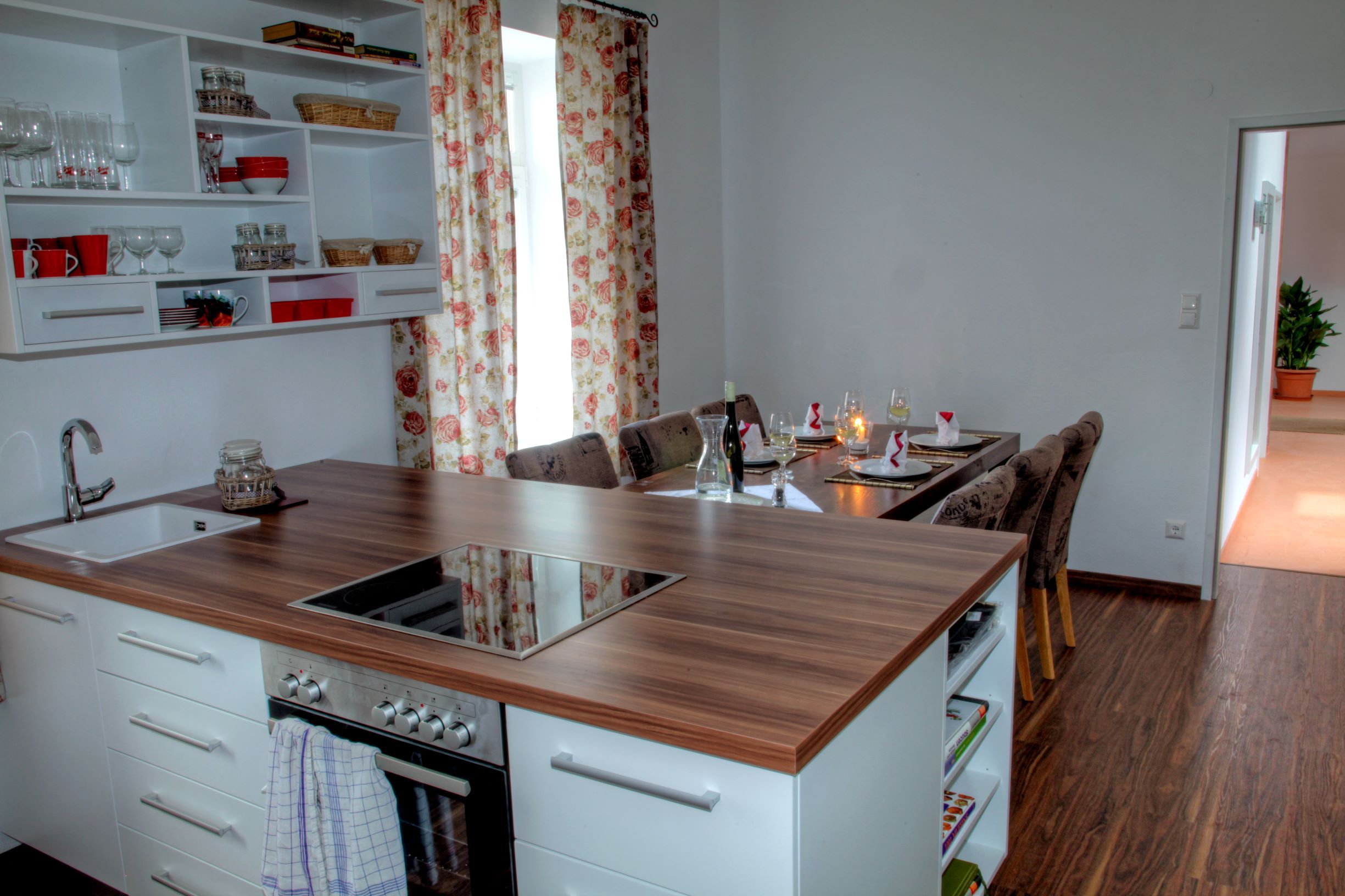 Modern kitchen with dining table in a loft, decorated with floral pattern curtains.