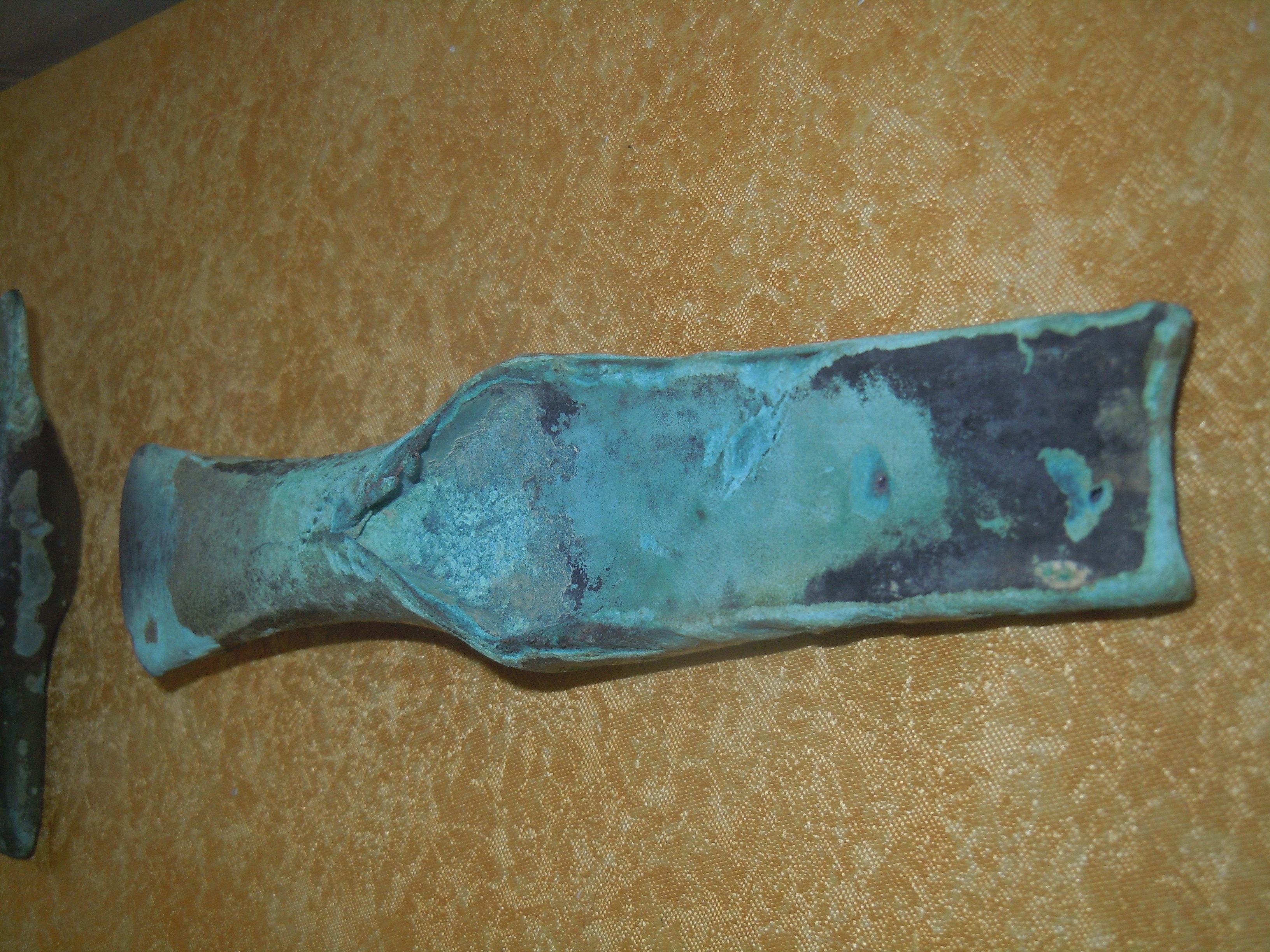 An old, oxidized metal tool on a yellow background.