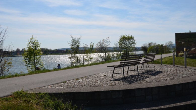 Two benches with a view of a river in sunny weather.