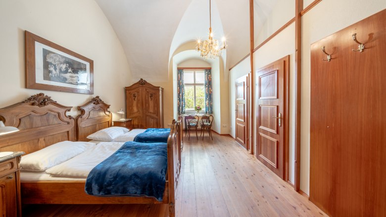 StiftAltenburg_Double room, © Martin Mathes An elegant double room with antique wooden furniture, a chandelier and a window with a view of the greenery.