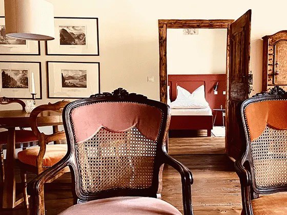 Cozy apartment with antique furniture and wooden floor, view into the bedroom with double bed.