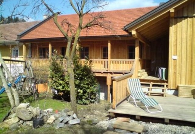Wooden building with terrace and garden in the foreground.