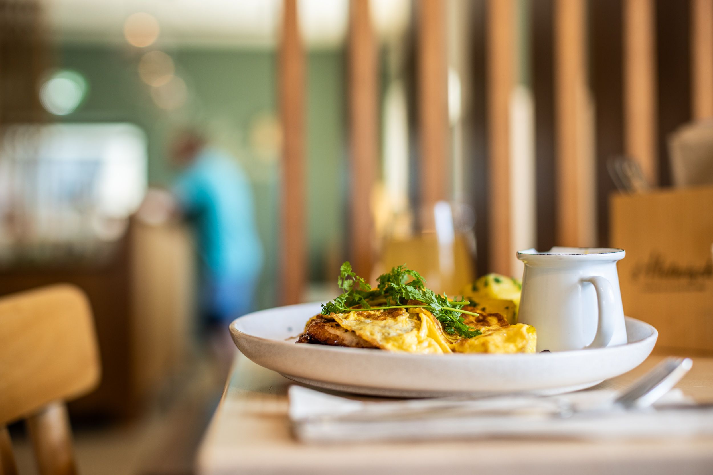 A plate with omelette and herbs on a table in a restaurant.