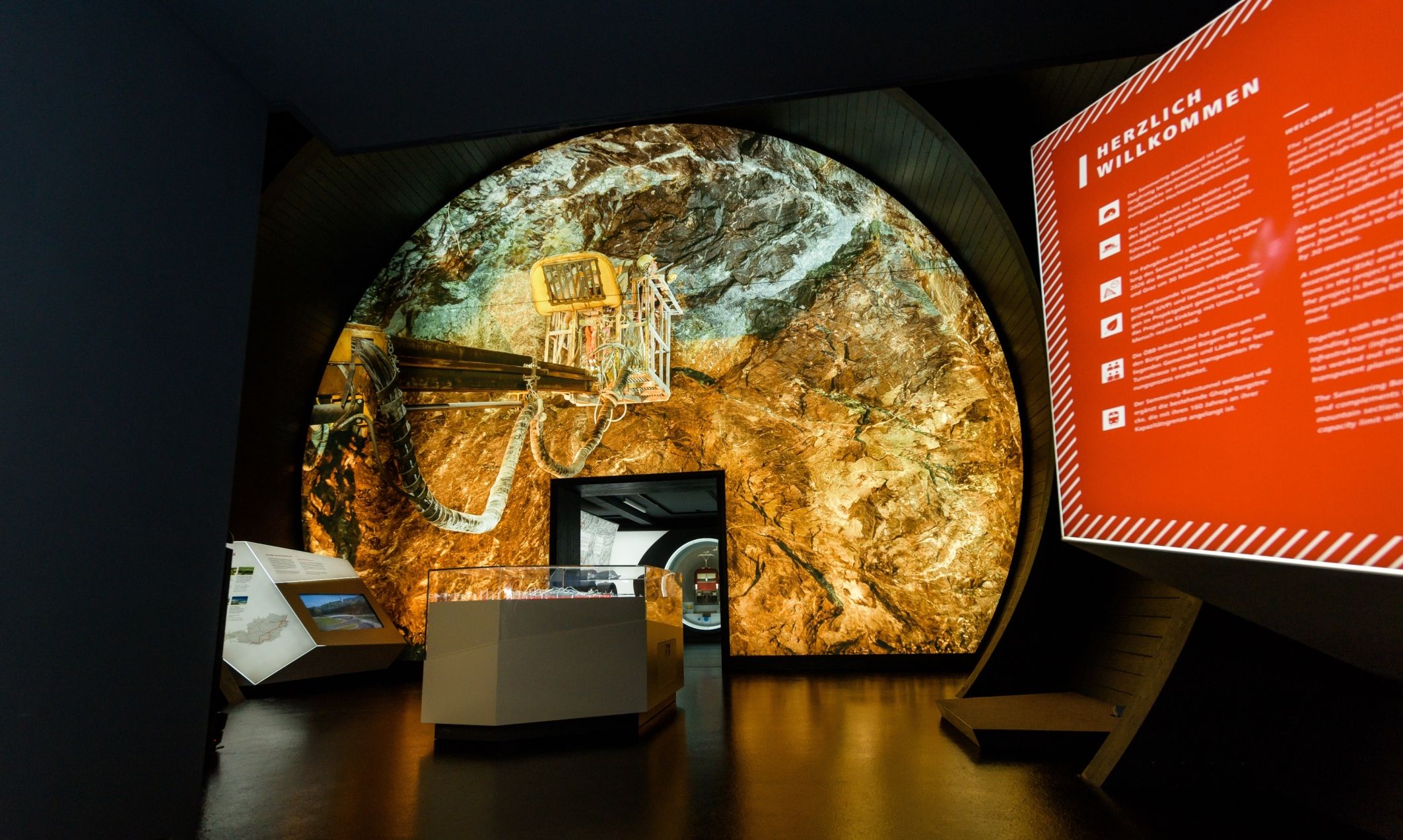Interior view of the Gloggnitz info box with a large projection of a tunnel and an information board.