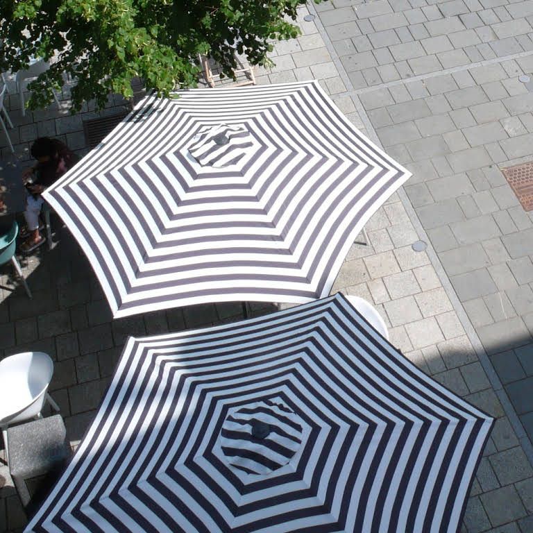 Two striped parasols on a paved square, photographed from above.