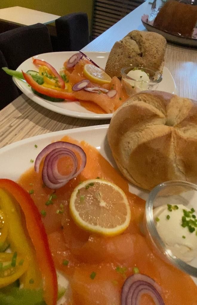 Breakfast plate with salmon, onions, lemon, peppers and bread rolls.
