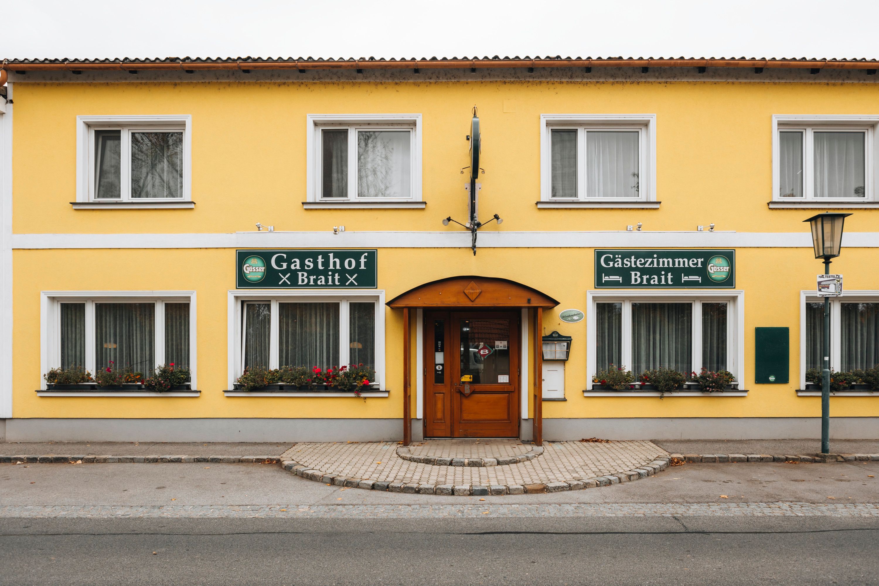 Yellow building with signs 'Gasthof Brait' and 'Gästezimmer Brait'.