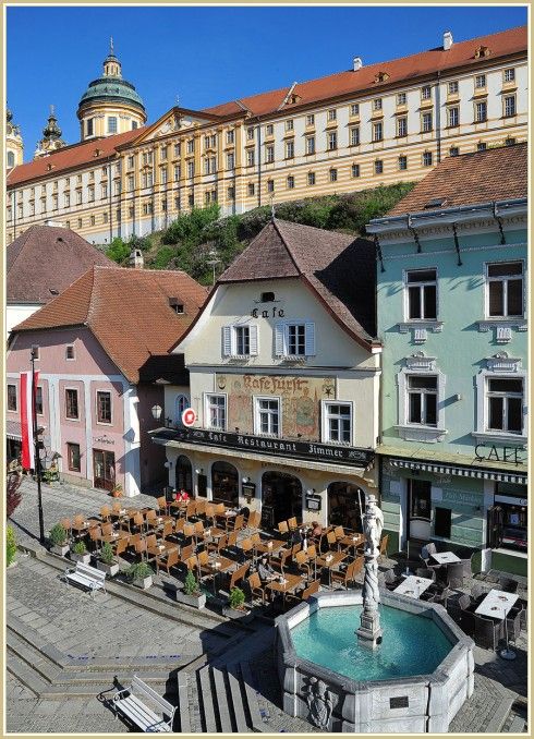 Historic buildings with café and fountain in the foreground.