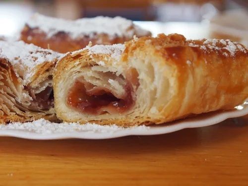 Close-up of pastries with fruit filling and powdered sugar on a plate.