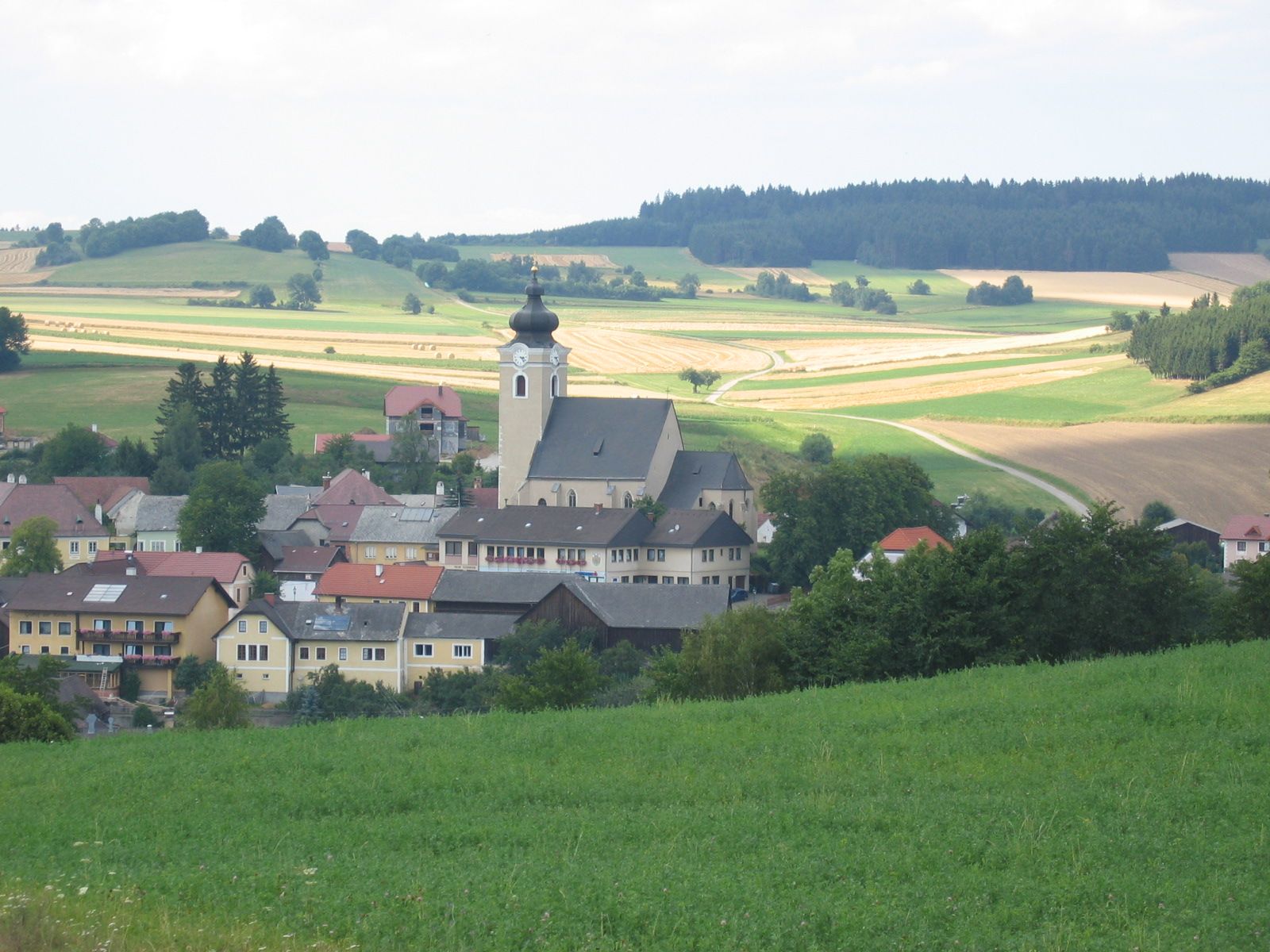 Rural community with church and fields in the background.