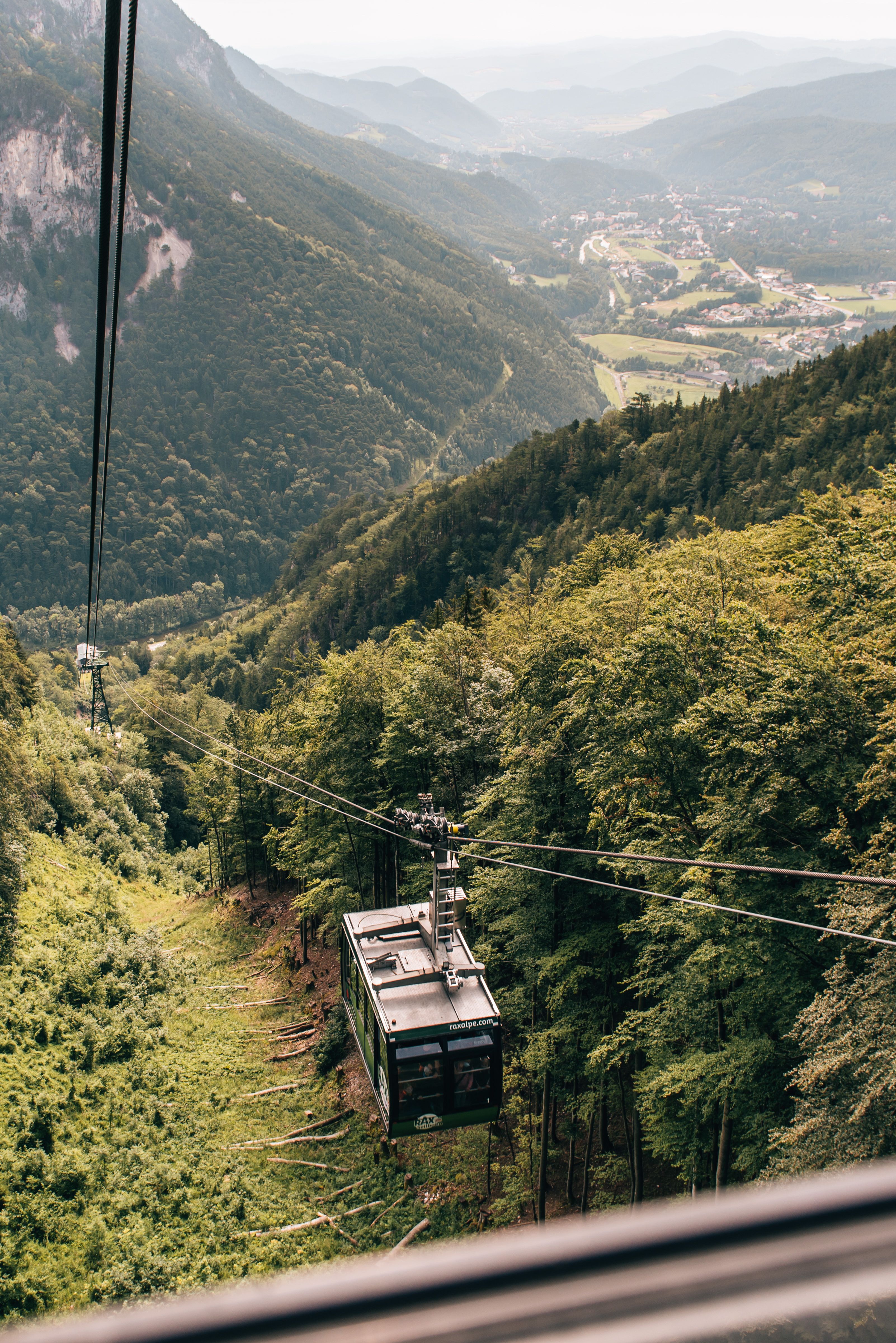 Cable car in the mountains with views of wooded slopes and valleys.