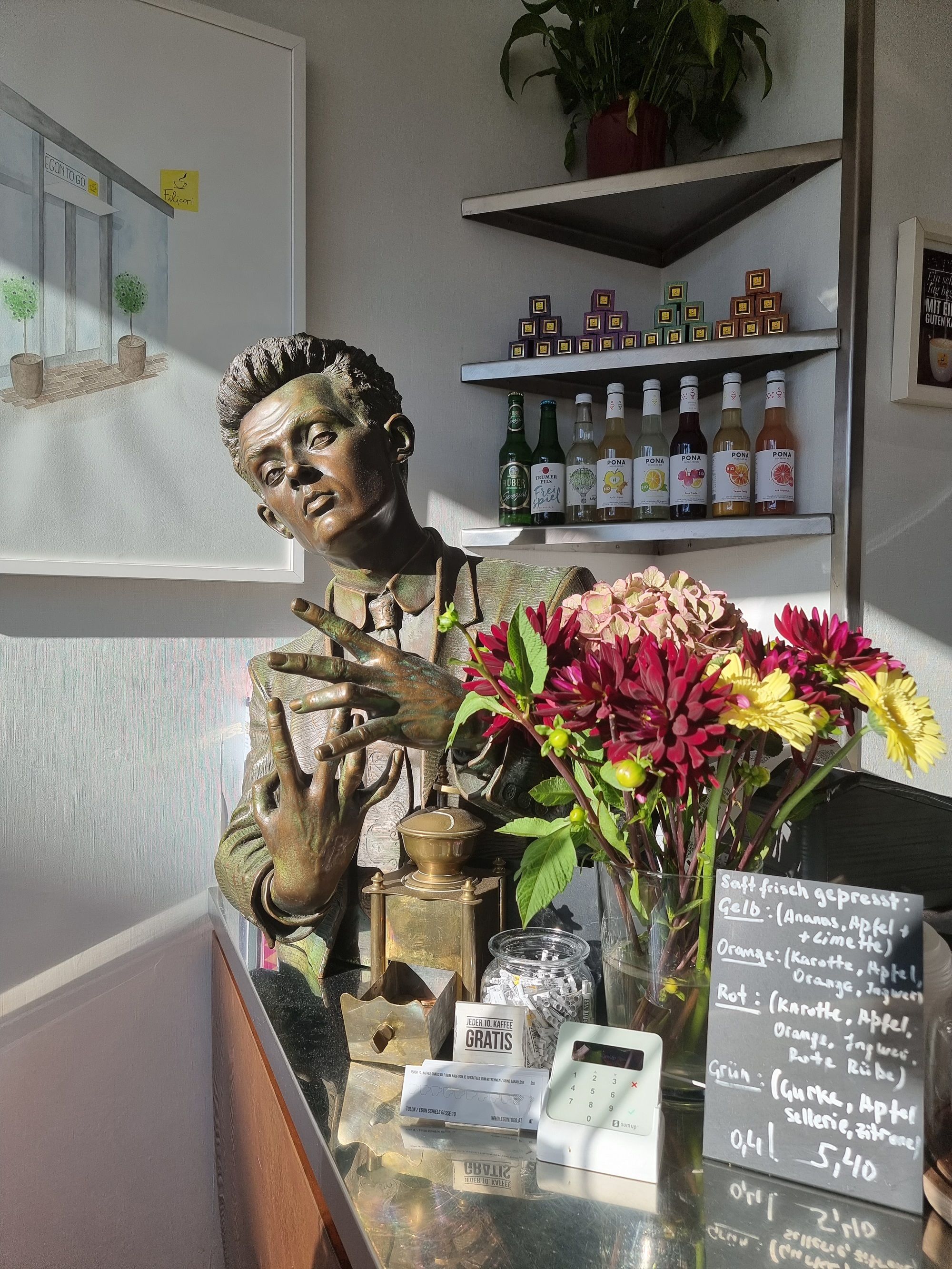 Egon Schiele statue in window with bouquet of flowers