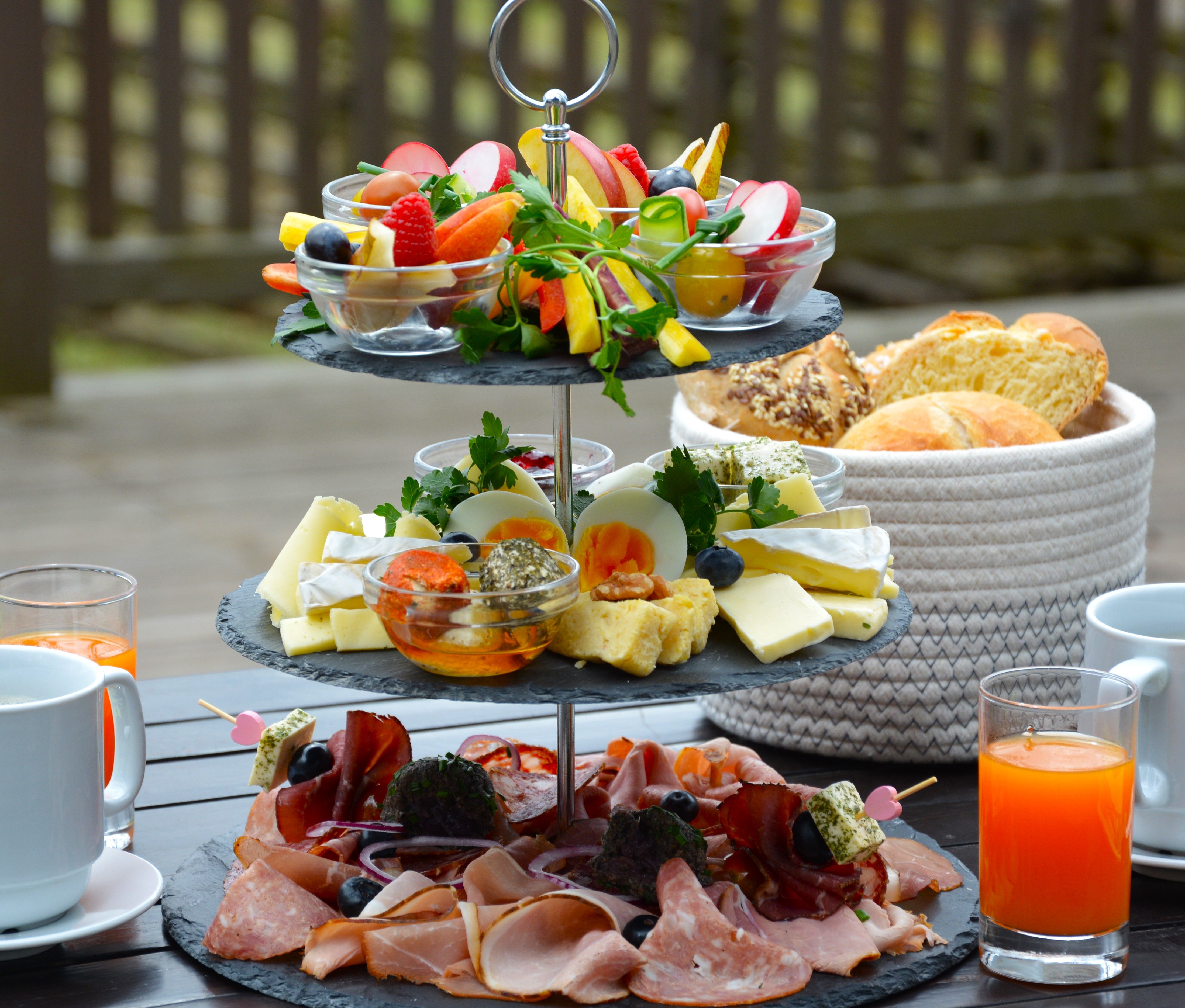 Shelf with cold cuts, cheese and vegetables, drinks and a bread basket next to it.