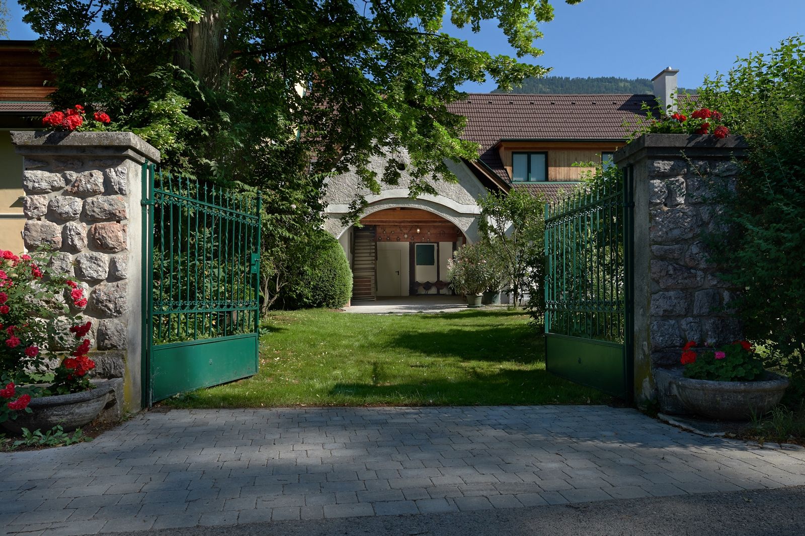 Open green gate leads to a house with garden.