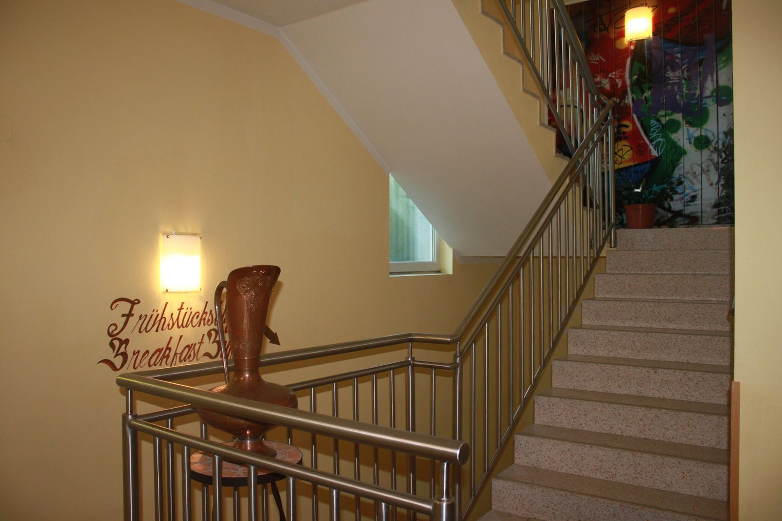 Staircase with banister, wall decoration and vase.