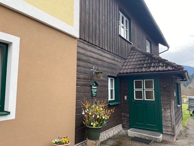 Entrance of a traditional house with wooden paneling and green door frame.