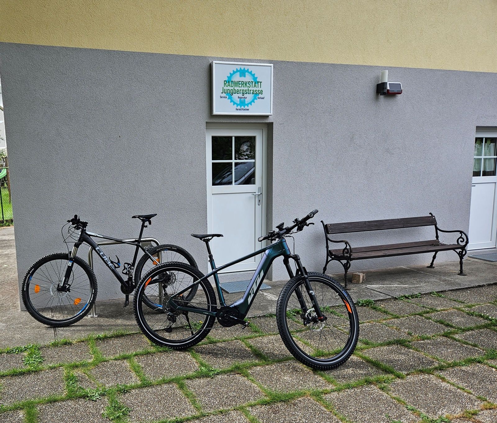 Two bicycles in front of a workshop with the sign 'Radwerkstatt Jungbergstrasse'.