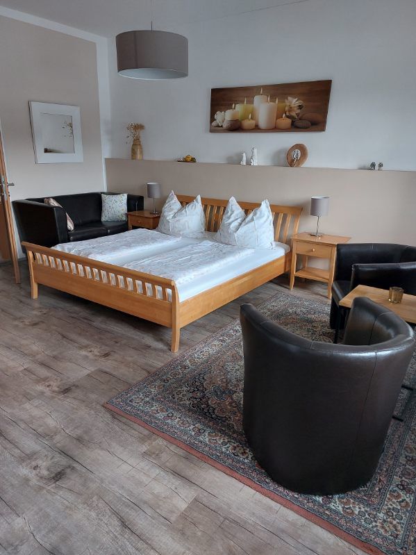 Cozy guest room with double bed, leather armchairs and decorative picture on the wall.