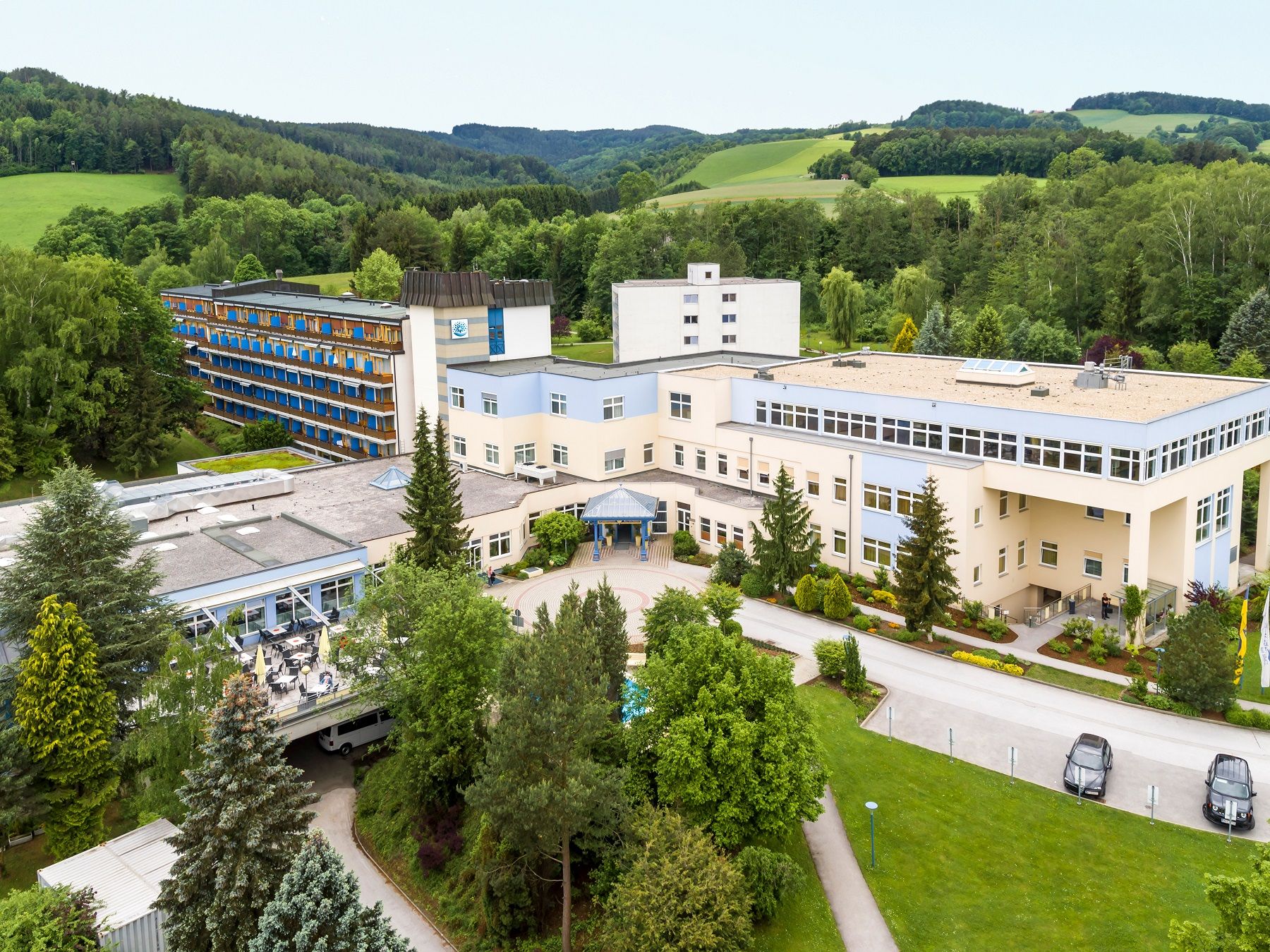 Aerial view of a large building complex in a green landscape.