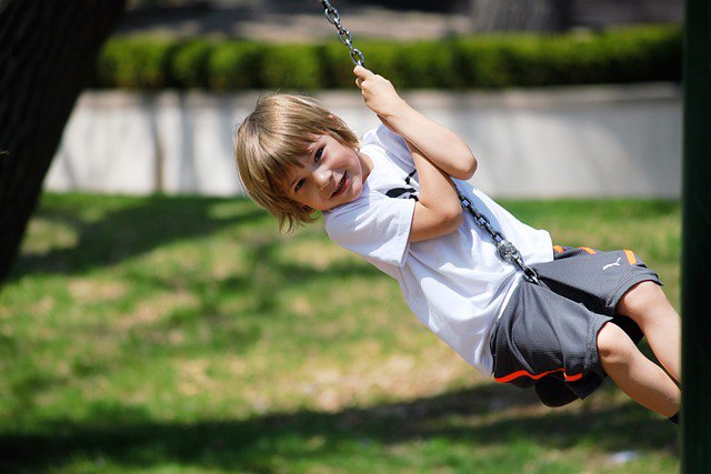 A child swings happily on a swing in a playground.