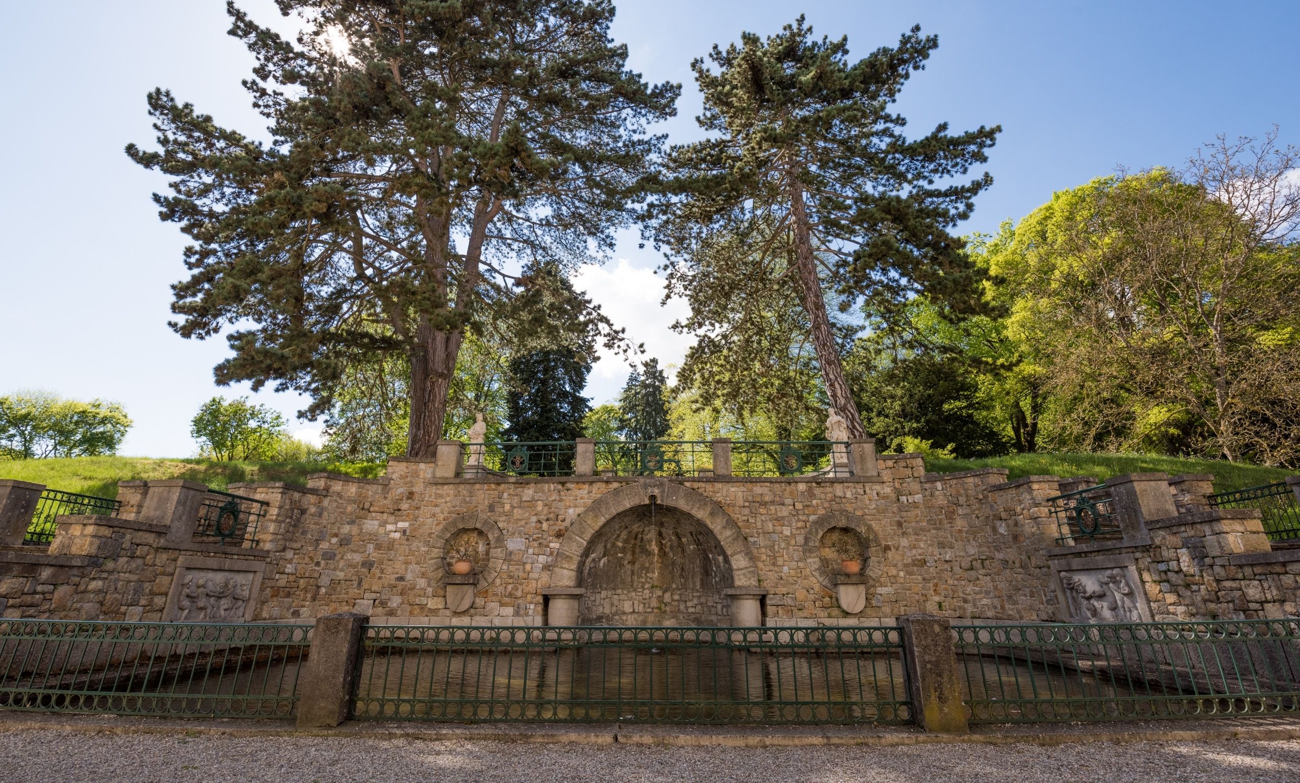 Stone wall with two large trees and decorative elements in the castle garden.