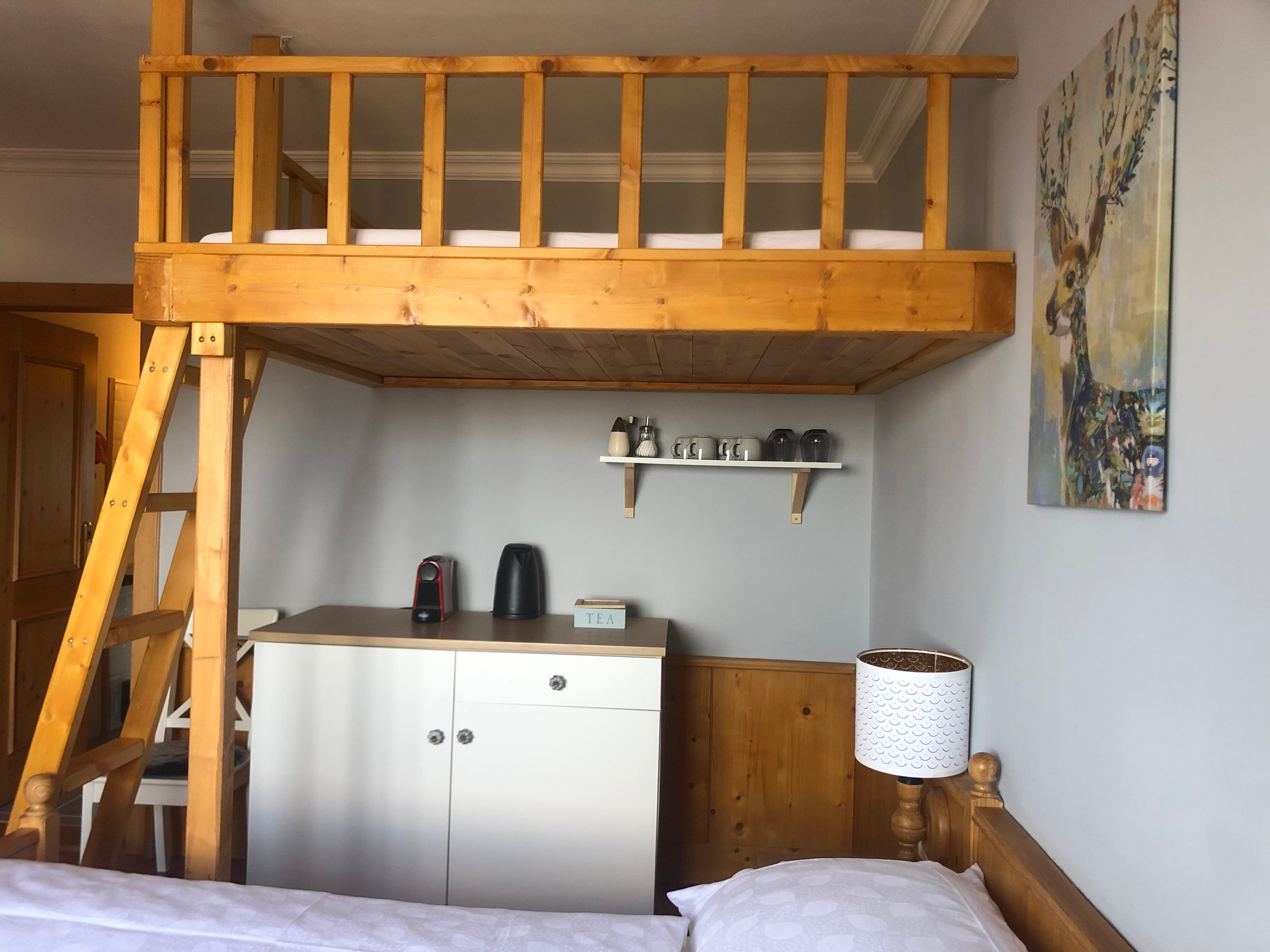 Room with loft bed, tea station and deer picture on the wall.