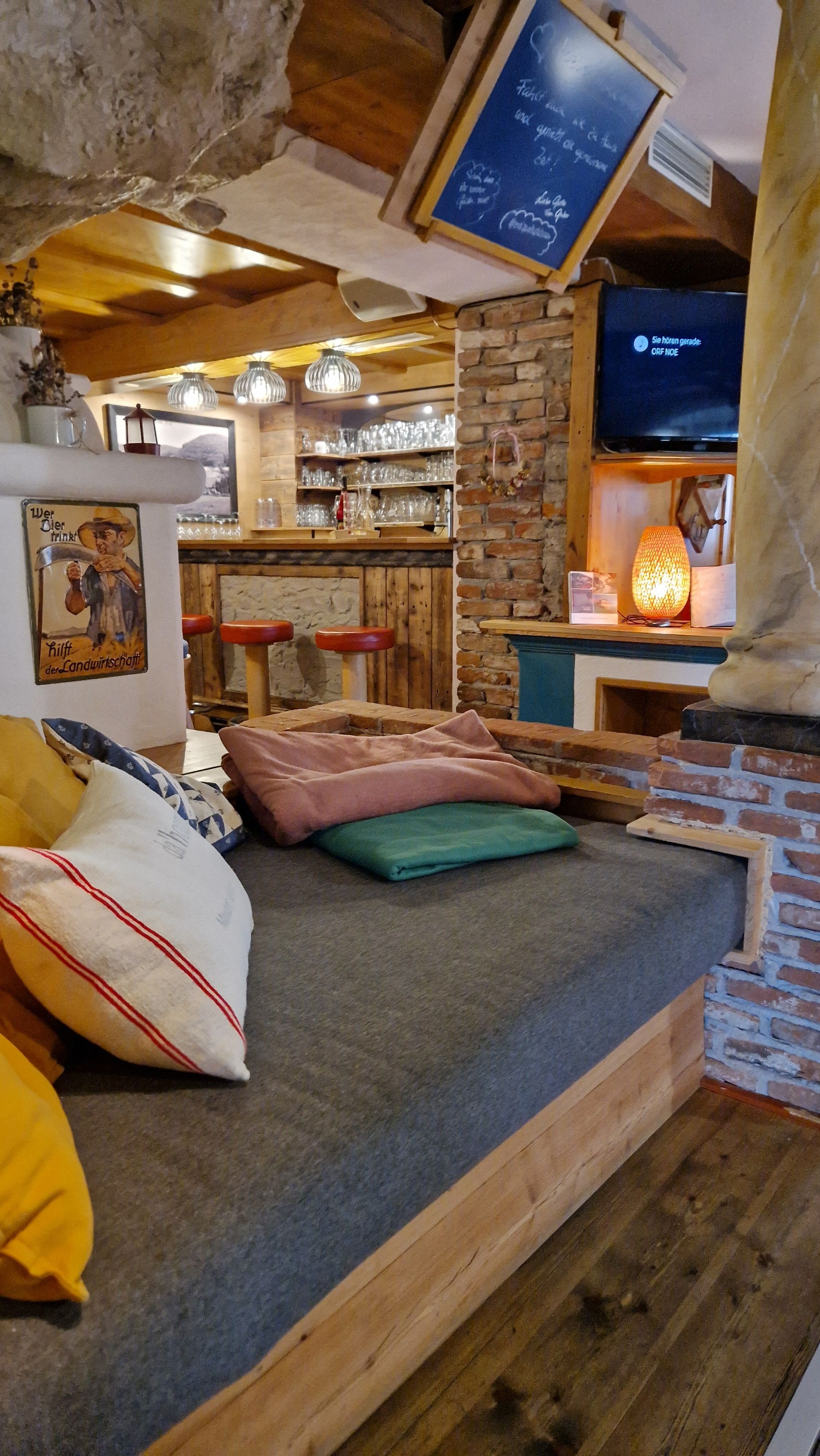 A cozy interior with wooden furniture, pillows, and a bar in the background.