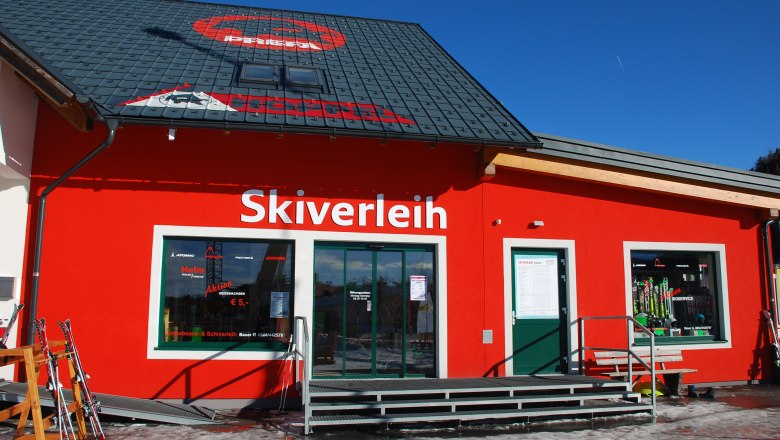 A red building with the words 'ski rental' and ski equipment in the shop window.